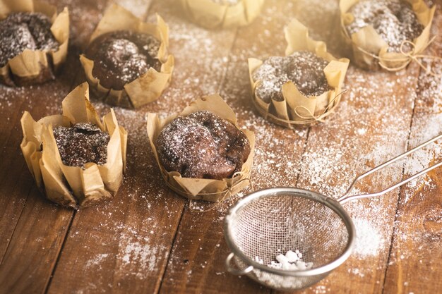 Muffins au chocolat savoureux dans du sucre en poudre sur la table