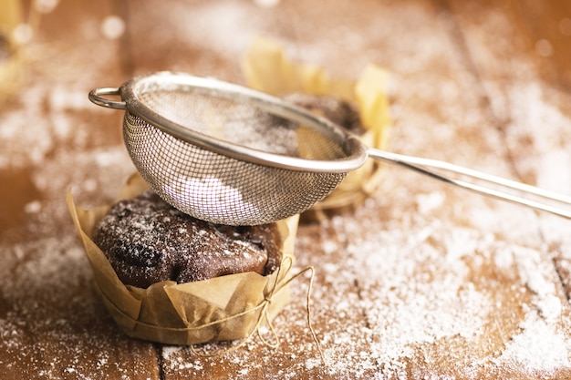 Muffins au chocolat savoureux dans du sucre en poudre sur la table