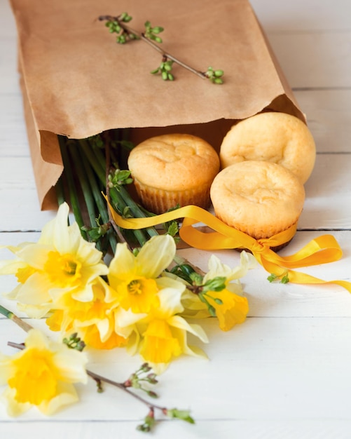 Muffins au citron dans un sac en papier Pâtisseries fraîches de la boulangerie Dessert et bouquet de fleurs