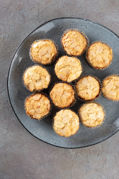 Muffins au fromage cottage décorés de flocons d'amandes sur une assiette bleue.