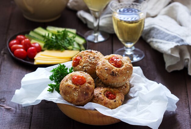 Muffins au fromage, fromage cottage et tomates, légumes et fromage servis avec du vin.