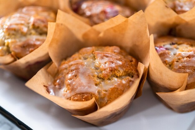 Muffins aux canneberges fraîchement cuits dans des moules à muffins en papier brun.