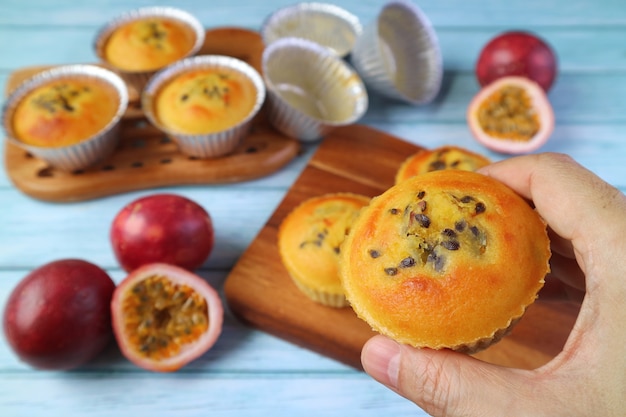 Muffins aux fruits de la passion maison cuits au four dans la main contre la table de cuisine en désordre floue