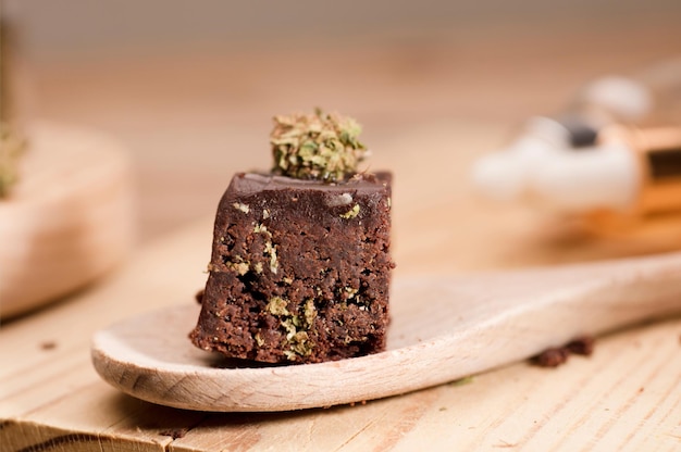 Muffins cupcake au chocolat avec des bourgeons de cannabis dans un pot d'huile cuillère en bois