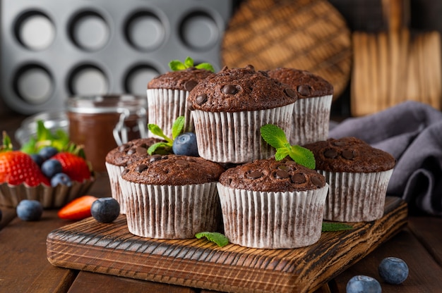 Muffins ou cupcakes au chocolat avec des gouttes de chocolat avec des baies fraîches et de la menthe