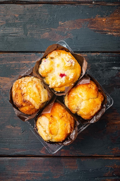 Muffins dans une boîte en plastique sur une vieille table en bois sombre fond vue de dessus mise à plat