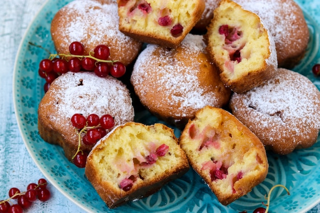 Muffins faits maison avec des baies, saupoudrés de sucre en poudre, disposés sur une table en bois bleue, style rustique