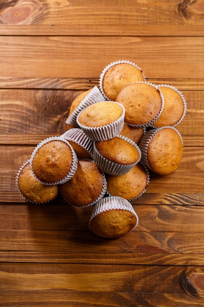 Photo muffins faits maison dans du papier d'emballage sur planche de bois