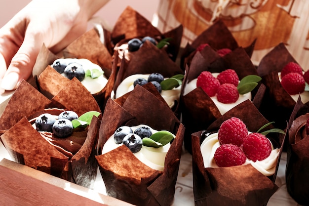Muffins des fêtes avec crème et baies dans un emballage individuel en papier