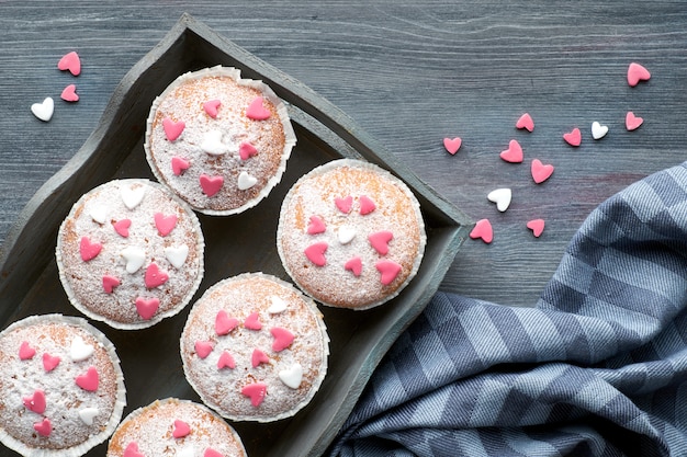 Muffins saupoudrés de sucre avec des coeurs de glaçage fondant rose et blanc
