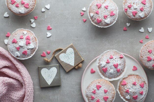 Muffins saupoudrés de sucre avec des cœurs glaçants fondants roses et blancs