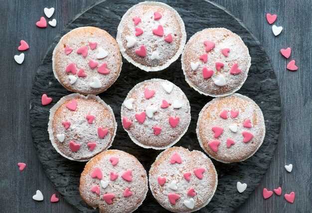 Muffins saupoudrés de sucre avec des cœurs glaçants fondants roses et blancs