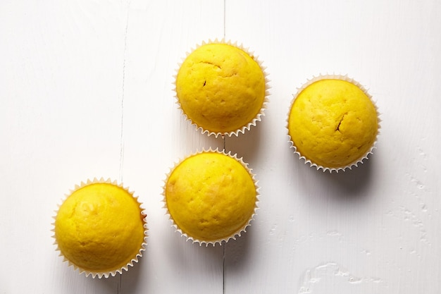 Muffins sur table blanche, mise à plat. Cupcakes sur fond en bois, vue de dessus. Boulangerie maison