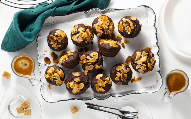 Muffins vegan avec chips de banane et d'amande avec espresso sur plateau.