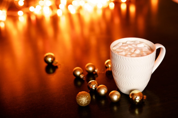 Mug blanc avec chocolat chaud et guimauves sur la table brun foncé