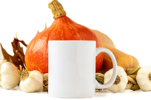 Mug blanc sur fond de citrouille et d'ail