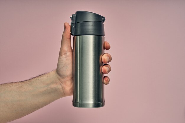 Mug en métal thermos à la main sur rose