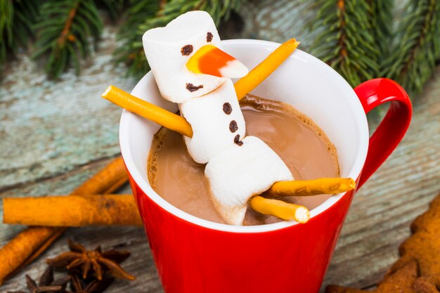 Mug rouge au chocolat chaud avec bonhomme de neige à la guimauve fondue