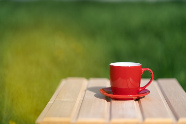 Mug rouge sur une table en bois et fond vert