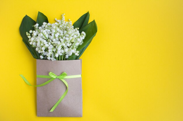 Muguet dans une enveloppe attachée avec un ruban vert sur jaune