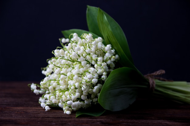 Muguet sur table en bois foncé. Bouquet de muguet.