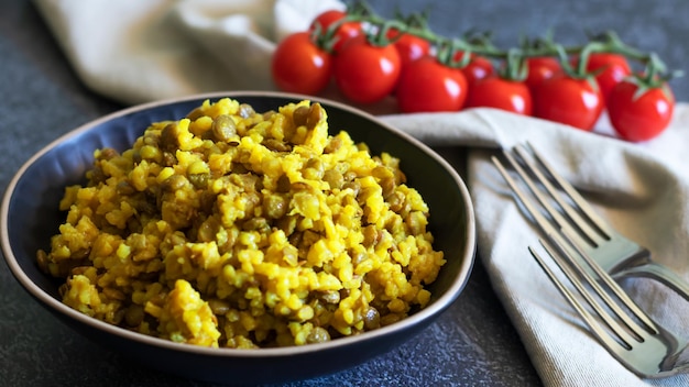 Mujadara à base de lentilles et de riz sur fond sombre avec des textiles clairs