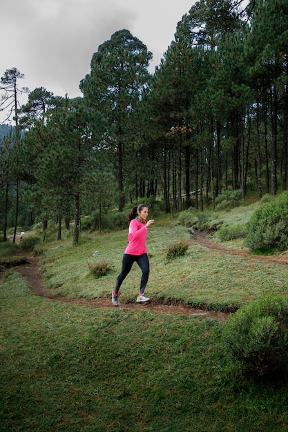 Mujer corriendo en un sendero del bosque con arboles al fondo