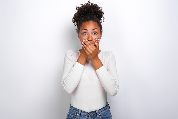 Mulâtre choquée femme se ferma la bouche par ses mains et regardant avec horreur