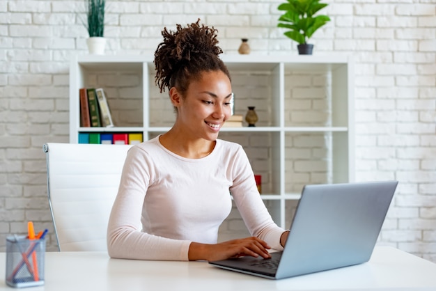 Mulâtre femme travaillant sur un ordinateur portable dans le bureau en regardant l&#39;écran et en tapant.