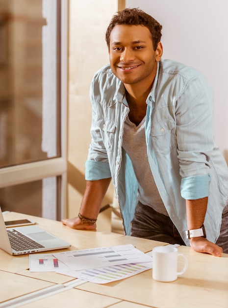 Mulatto homme d'affaires sourient tout en travaillant dans le bureau.