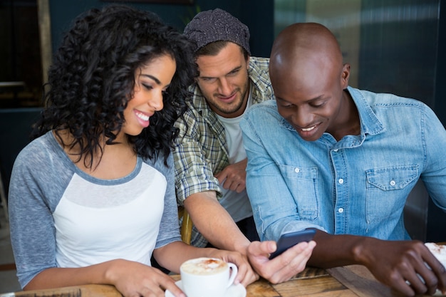 Multi-ethnique amis masculins et féminins à l'aide de téléphone mobile dans un café