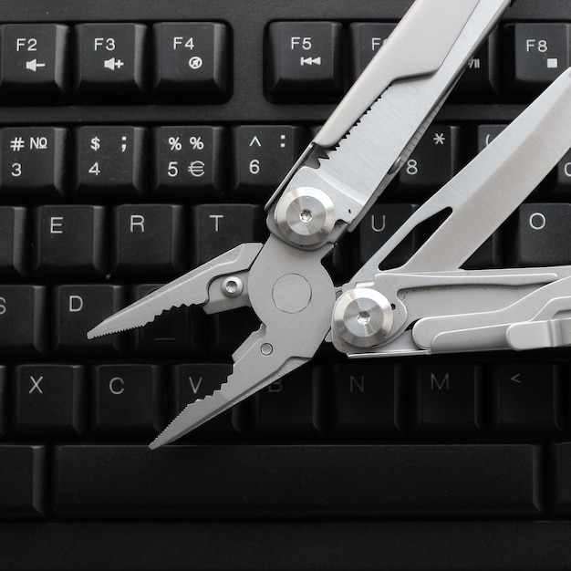 Multi-tool Pliers Resting on a Black Keyboard