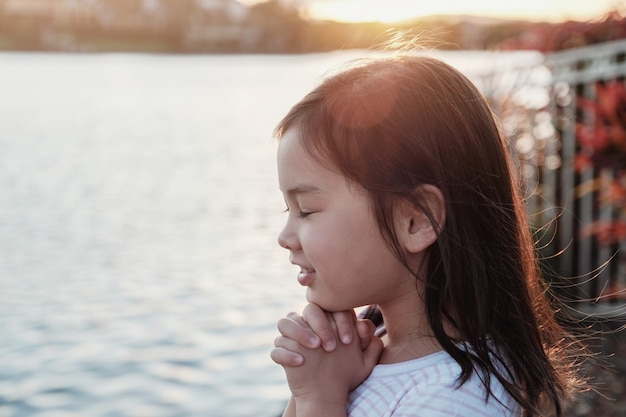 Multiculturel petite fille priant avec fond de tournesol