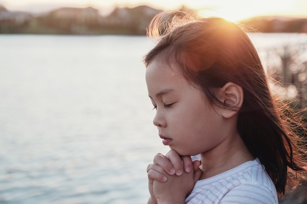 Multiculturel petite fille priant avec fond de tournesol