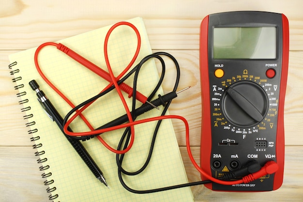 Photo multimètre numérique avec sondes et carnet jaune sur table en bois