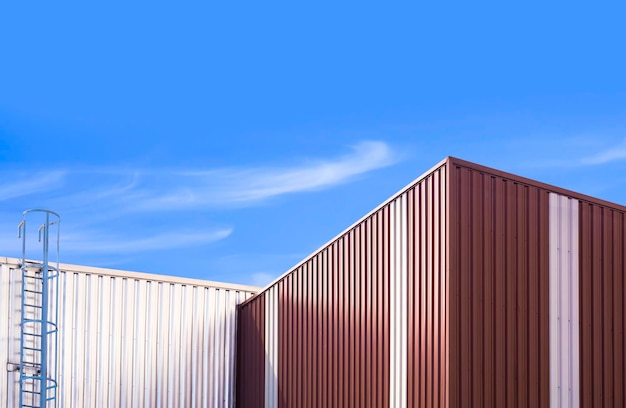 Mur en acier ondulé de 2 bâtiments d'entrepôt avec escalier métallique sur fond de ciel bleu