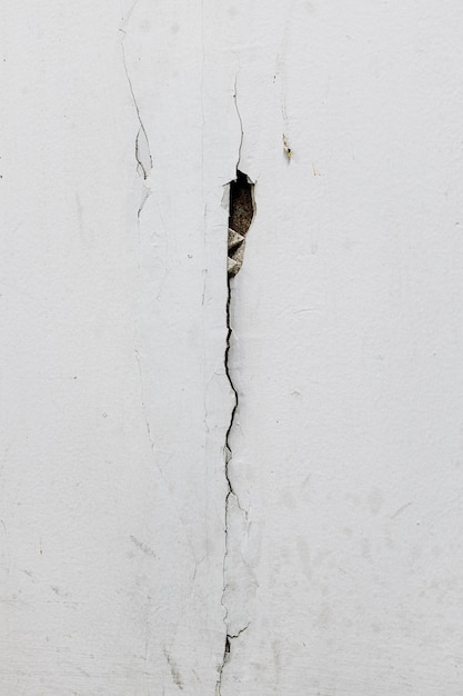 Le mur de béton blanc de texture a des fissures