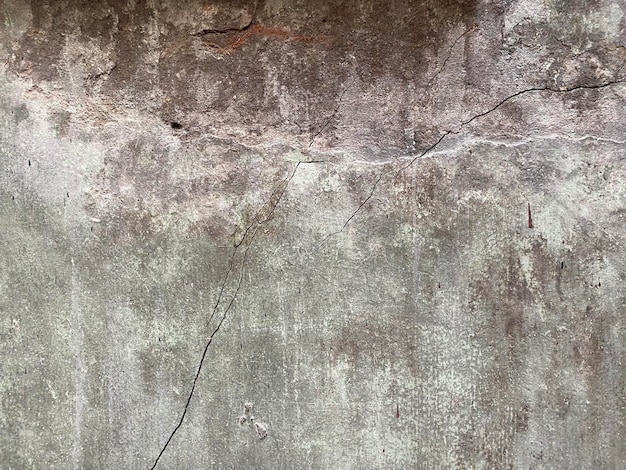 Un mur de béton fissuré avec une fissure au milieu.
