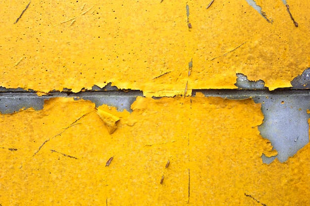 Mur en béton avec de la peinture écaillée jaune, orange vieux fissuré endommagé texture de fond clair rugueux