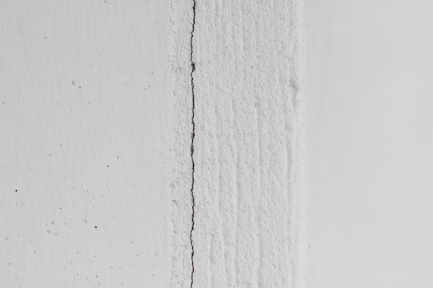 Mur de béton texturé blanc avec des points et une photo horizontale de fissure verticale