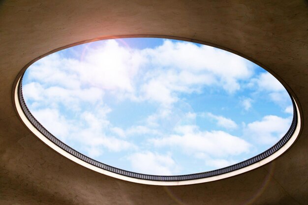 Photo mur blanc avec un trou qui est observé à l'extérieur du bâtiment avec des nuages dans le ciel