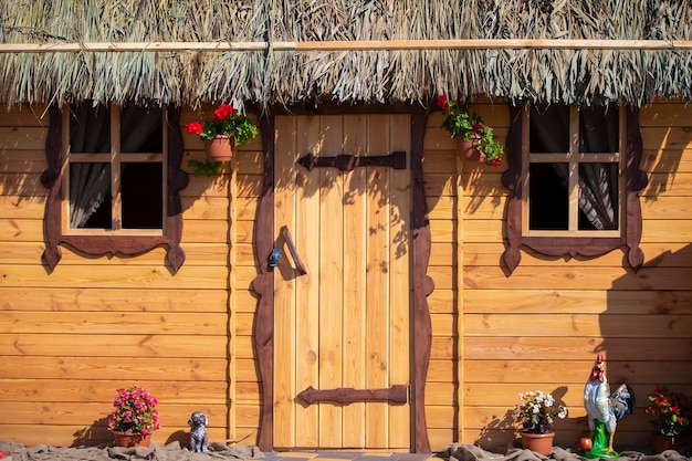 Mur en bois de fond d'une maison avec une fenêtre et un toit couvert de chaume