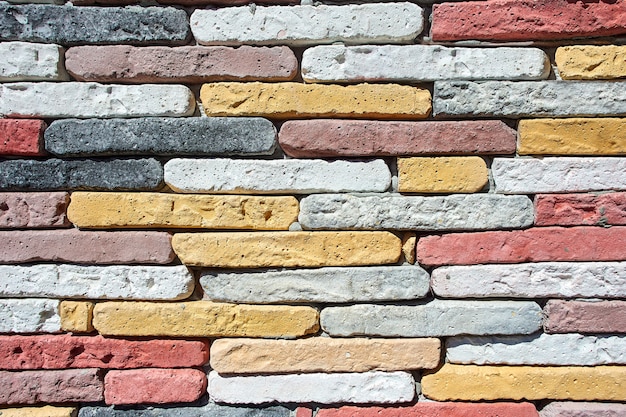 Mur de briques faites maison colorées comme texture pour le fond