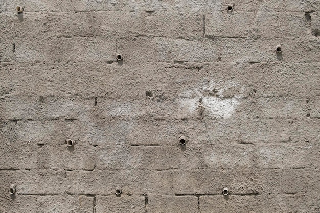 Mur de briques gris rugueux en ciment avec tuyaux de drainage pour éliminer l'humidité