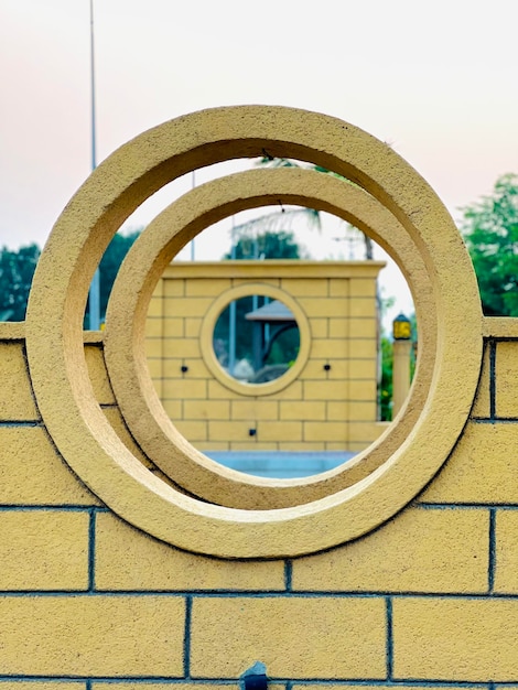 Un mur de briques jaunes avec un trou rond au milieu qui dit "le cercle"