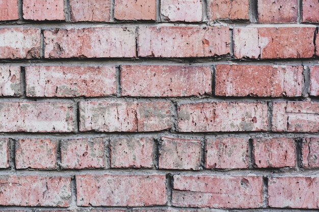 Mur de briques rouges recouvert de mortier avec des pierres très anciennes et fissurées