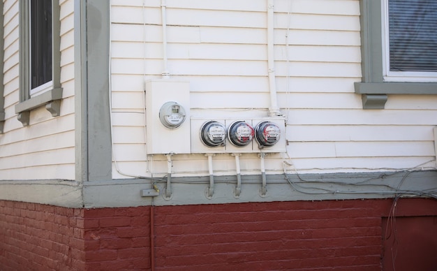 Un mur de briques rouges avec un tas de compteurs électriques dessus.