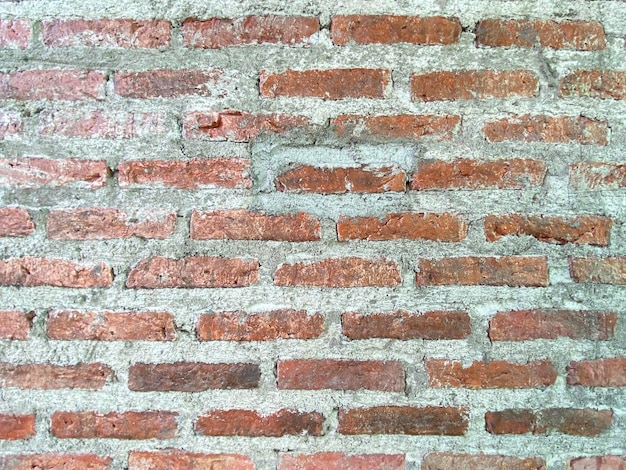 Un mur de briques avec une surface rugueuse et un petit trou au milieu.