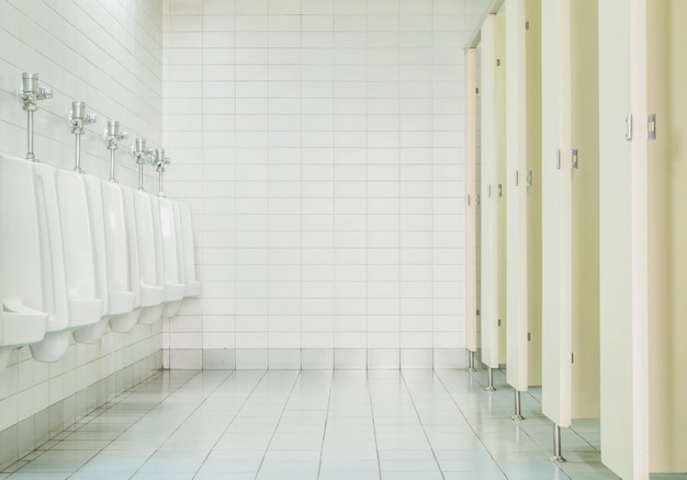 Mur de carreaux gros plan dans les toilettes de l&#39;homme avec vue de toilettes par des urinoirs et petite pièce