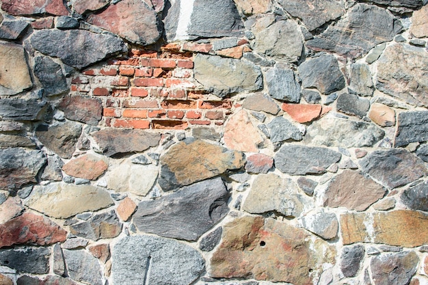 Mur de grandes pierres naturelles avec un morceau de brique, fond naturel.